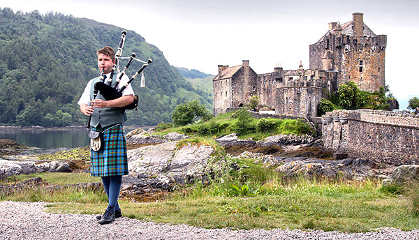 Eilean Donan Castle and bagpiper, Scotland, UK